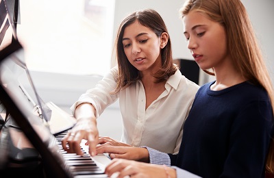piano teacher and student
            sitting at a piano